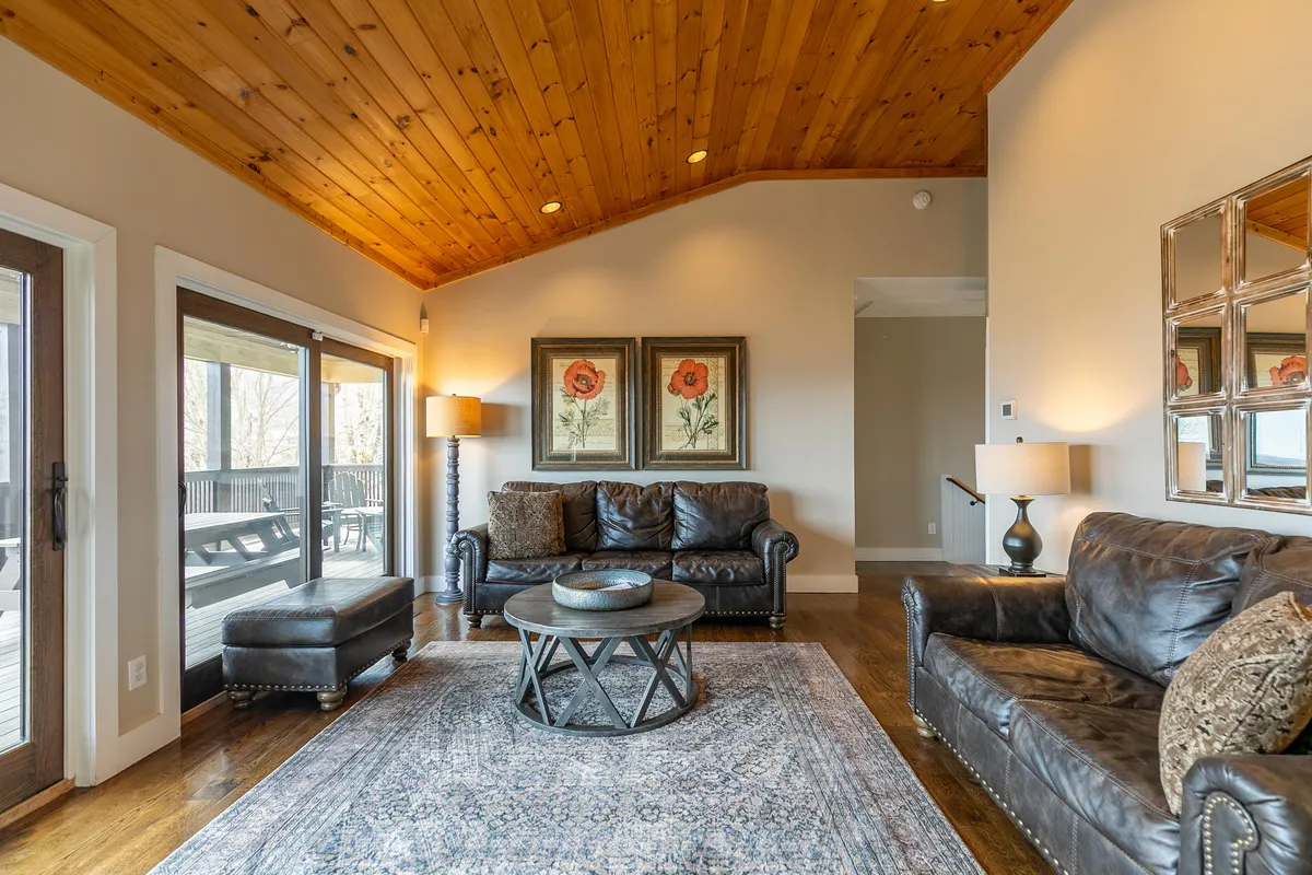 A welcoming living space with a wooden ceiling, comfortable sofas, and framed floral art. The room opens onto the deck, where sunset views can be enjoyed, reinforcing the connection between indoor relaxation and outdoor exploration. The setup encourages conversation and shared experiences.