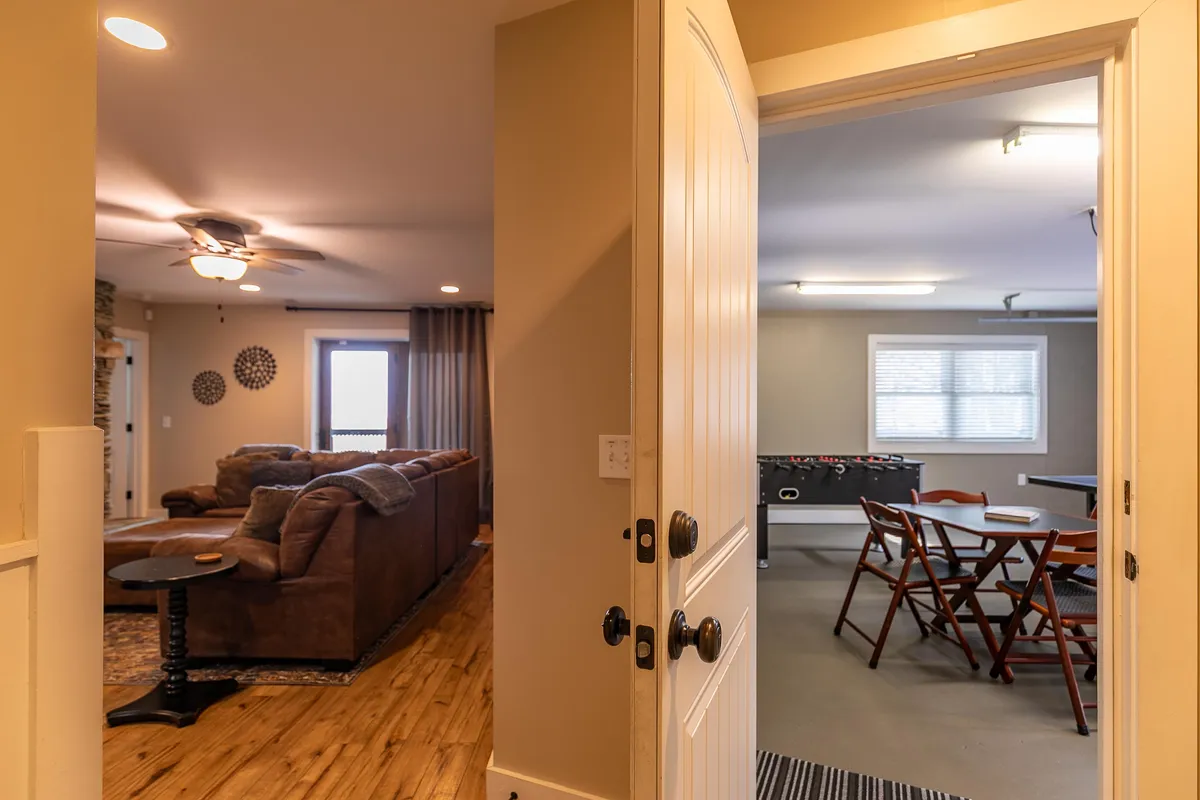 An inviting entryway leading to a living room with visible game room table. The open space encourages socializing and casual game nights, with comfortable seating and warm lighting that set the stage for group activities.