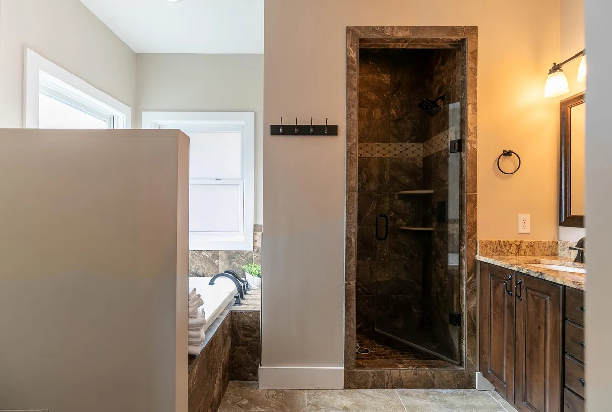 A spa-inspired bathroom featuring a modern bathtub, spacious shower stall, double vanity with mirrors, and soft lighting. The calm colors and elegant fixtures establish a serene, indulgent environment perfect for relaxation.