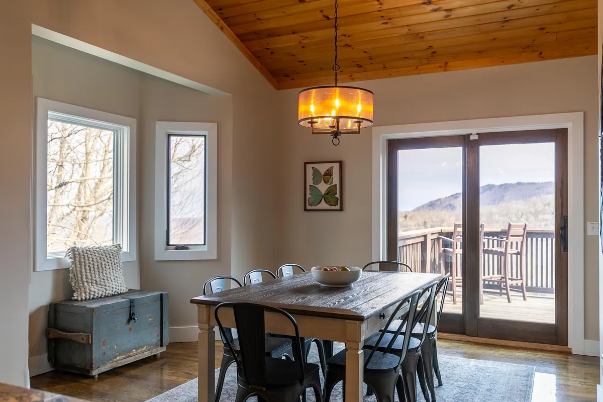 A dining area with a large table under a chandelier, situated near sliding doors that likely lead to a deck or outdoor space. The setup is ideal for shared meals, celebrations, and transitioning between indoor dining and al fresco experiences.